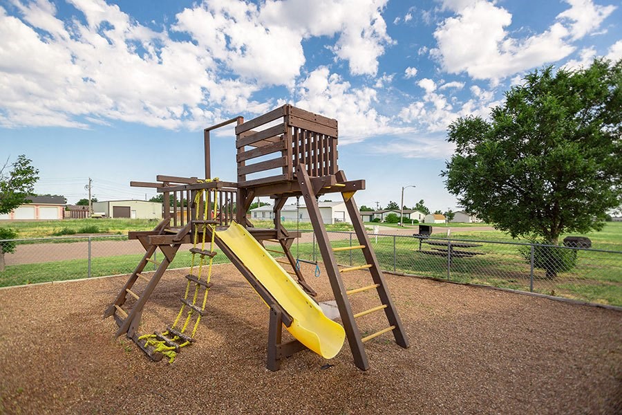 A wooden playground structure with a yellow slide.