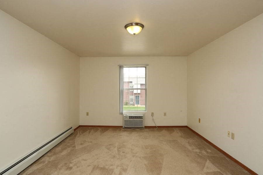 Empty room with a window and a carpet on the floor.