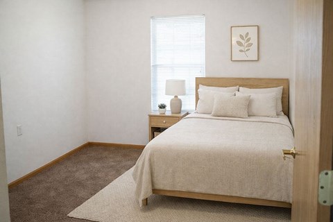 A bedroom with a bed, nightstand, and lamp.