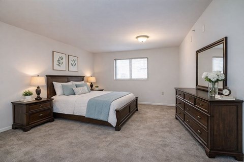 A bedroom with a bed, dresser, and mirror.