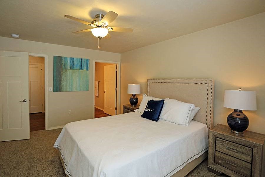 a bedroom with a large white bed and a ceiling fan