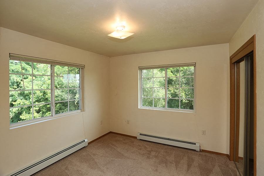 an empty living room with two windows
