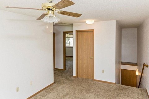 an empty living room with a ceiling fan and a closet