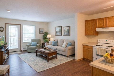 A living room with a couch, chair, and a table with a basket of fruit on it.