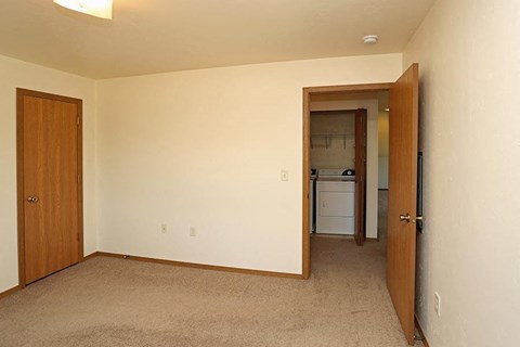 an empty living room with a door to a kitchen