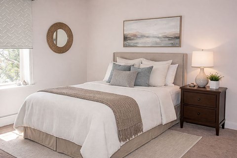 A bedroom with a large bed and a painting on the wall.