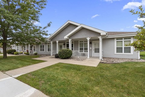 the front of a gray house with a sidewalk and grass