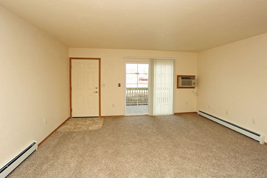 an empty living room with a door to a balcony
