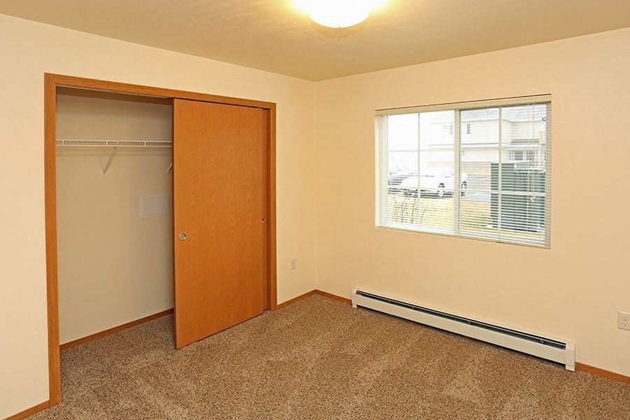 A room with a brown carpet and a wooden door.