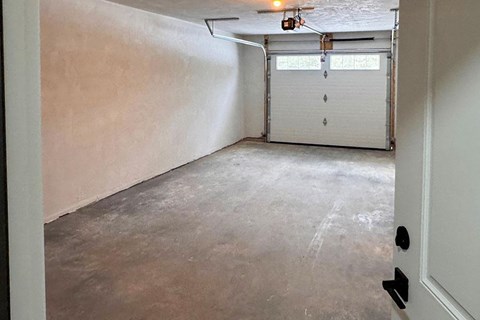 A room with a white garage door and a concrete floor.