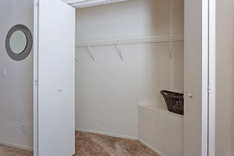 A white closet with a mirror and a basket on the shelf.