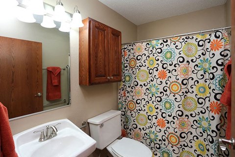A bathroom with a floral shower curtain and a white toilet.