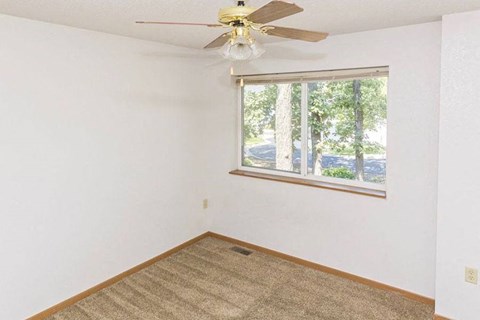 an empty room with a window and a ceiling fan