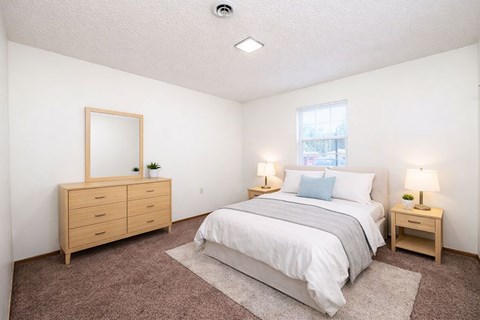 A bedroom with a bed, nightstands, and a dresser.