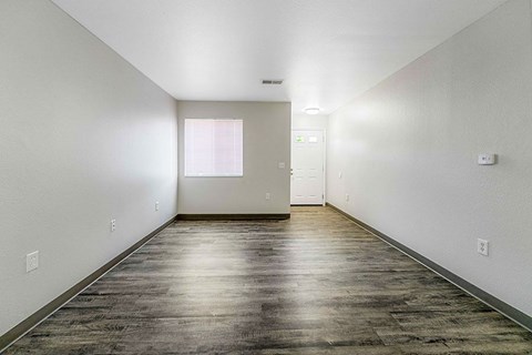 A long, empty hallway with wood flooring and white walls.