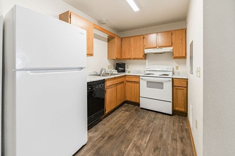 A kitchen with a white fridge, white stove, and wooden cabinets.