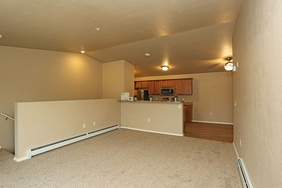 an empty room with a kitchen and a living room