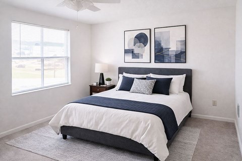 A bedroom with a bed, nightstand, and two framed pictures on the wall.