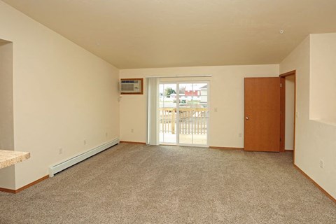 an empty living room with a door to a balcony