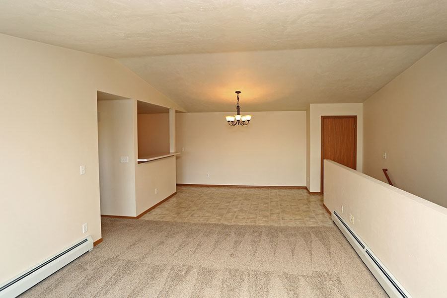 A spacious room with a carpeted floor and a chandelier hanging from the ceiling.