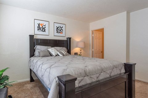 A bedroom with a large bed and two framed pictures on the wall.