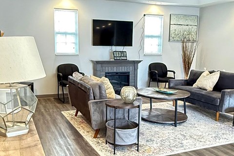 A living room with a fireplace and a television mounted above it.