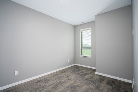 A room with a window and a carpeted floor.