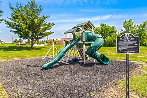 A playground with a green slide and a sign that says "Playground Rules".