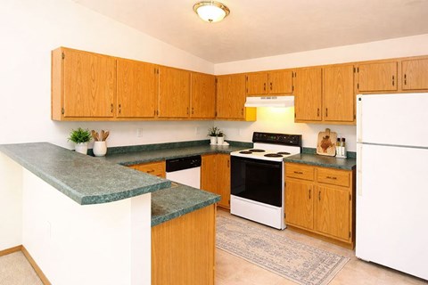 A kitchen with wooden cabinets and a green counter top.