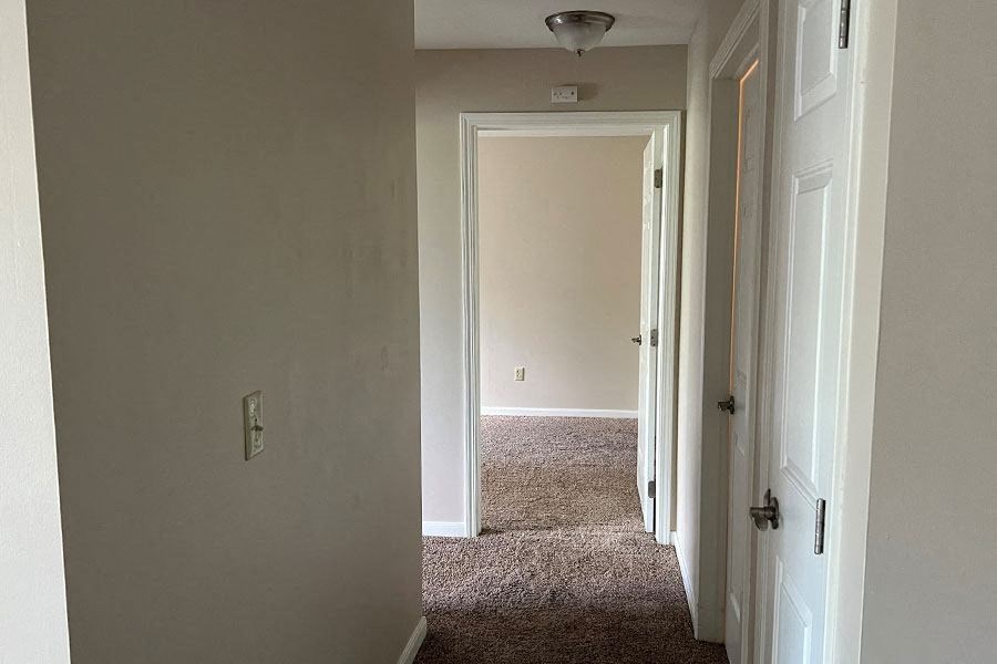 a hallway with a white door and a carpeted floor
