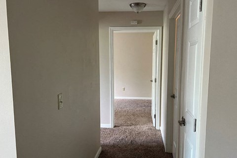a hallway with a white door and a carpeted floor