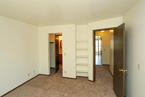 A room with a carpeted floor and two doors.