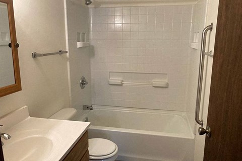 A white tiled bathroom with a toilet, sink, and bathtub.
