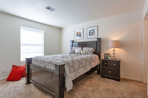 A bedroom with a bed, nightstand, and two pictures on the wall.