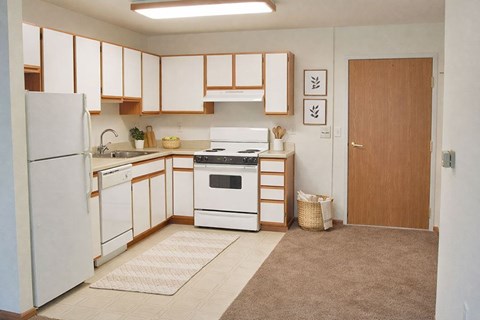 A kitchen with white appliances and wooden cabinets.
