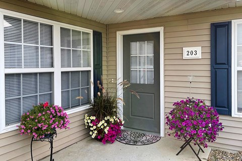 a front porch of a house with flowers and a gray door