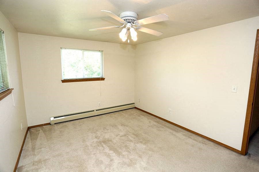 an empty room with a ceiling fan and a window