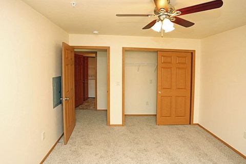 a living room with a ceiling fan and a closet