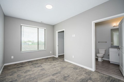 A room with a carpeted floor and a window with blinds.