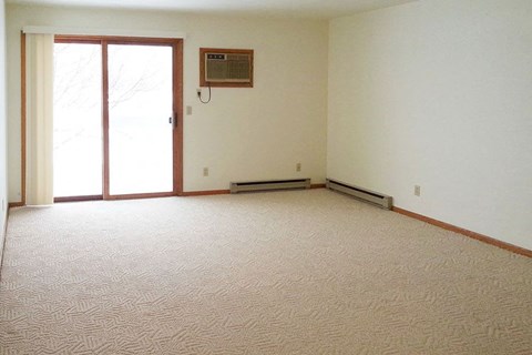 an empty living room with a heater and a window