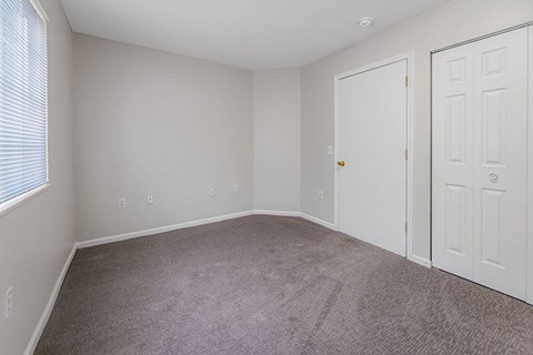 A room with a carpeted floor and two doors.