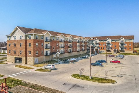 A large apartment complex with a parking lot in front.