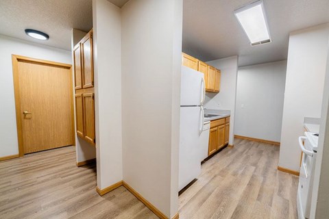 A kitchen area with a refrigerator, sink, and wooden floors.