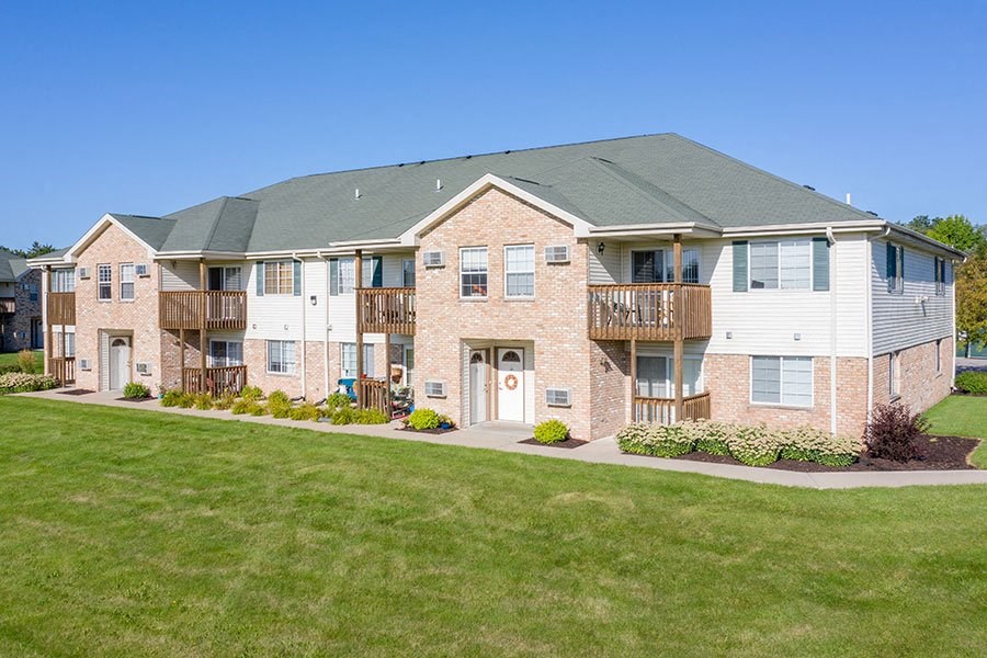 a brick apartment building with a green lawn