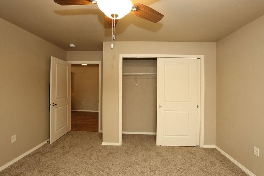 an empty bedroom with a ceiling fan and a closet