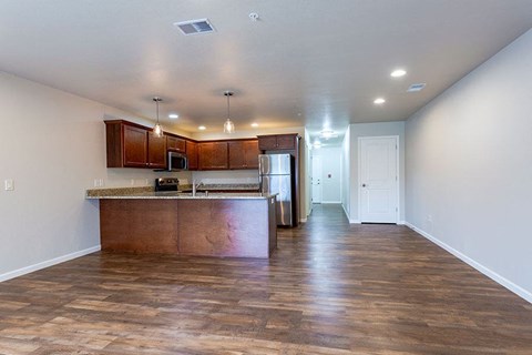 an empty kitchen with wood floors and a refrigerator