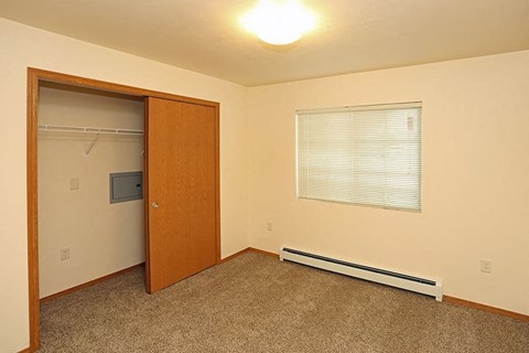 an empty room with a door to a closet and a window