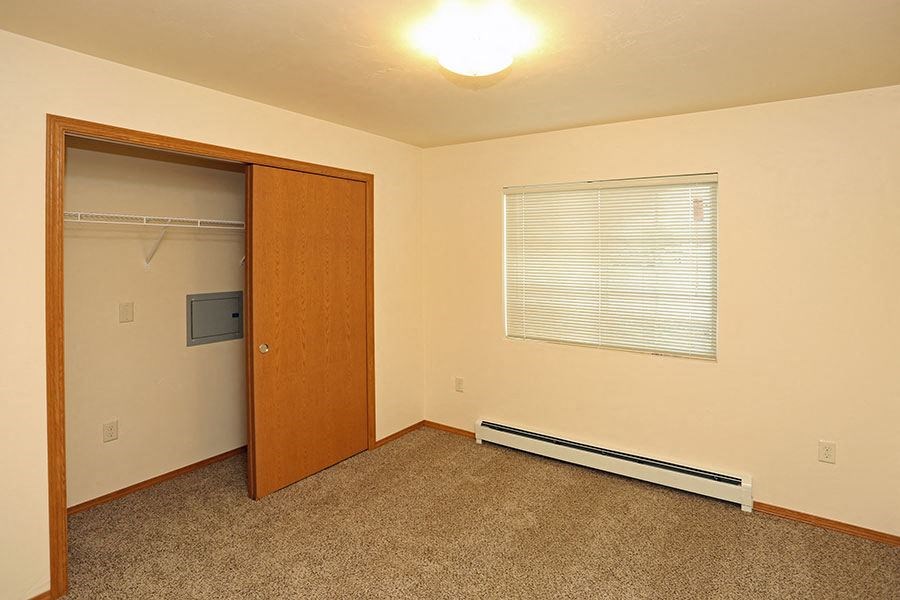 an empty room with a door to a closet and a window