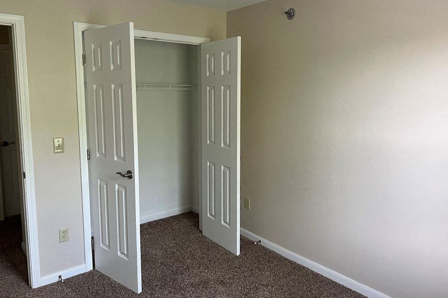 an empty room with a closet and two doors