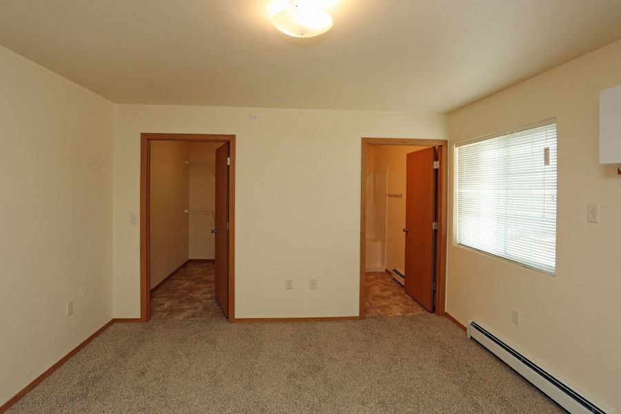 A room with carpeted floor and two doors.
